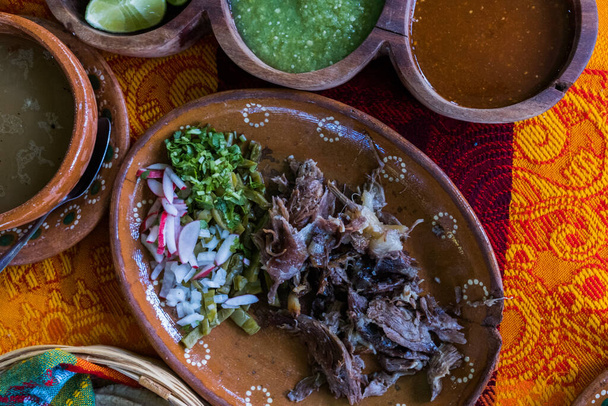 Мексиканці нарізали ягняче м "ясо, гарячий соус і бульйон на барвистій скатерці. - Фото, зображення
