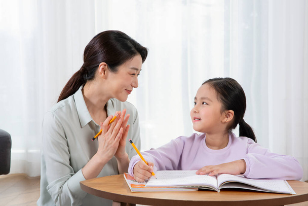 Asian mother helping young daughter study - Foto, Bild