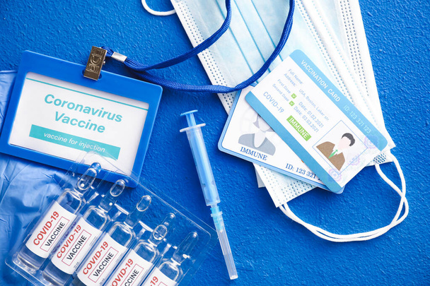 Covid-19 vakcina, orvosi maszkok, fecskendő és oltási kártyák színes háttérrel - Fotó, kép