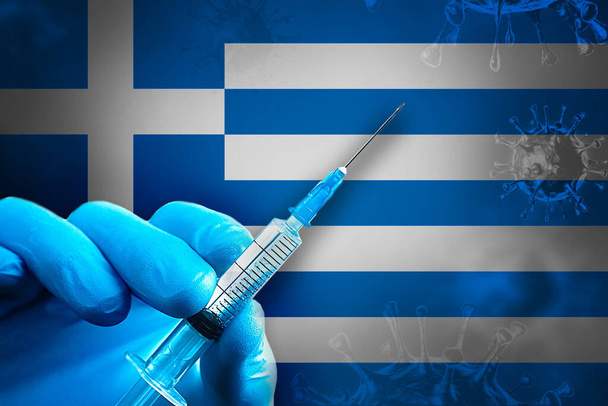 Řecko Covid-19 Vakcinační kampaň. Ruka v modré gumové rukavici drží injekční stříkačku s vakcínou proti viru covid-19 před vlajkou Řecka. Koncepce očkování proti koronaviru - Fotografie, Obrázek