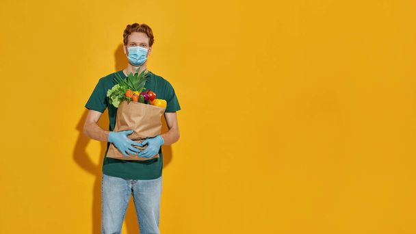 Young caucasian courier delivering packet with vegetables - 写真・画像