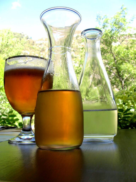 Bir bardak bira ve arka plandaki masada meyve suyu ve suyla birlikte iki sürahi. Sıcak yaz günü. - Fotoğraf, Görsel