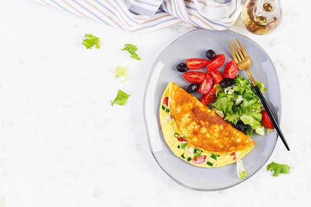 Keto snídaně. Omeleta se sýrem, rajčaty a zelenou cibulí na světlém stole. Italská frittata. Keto, ketogenní oběd. Pohled shora, režie, kopírovací prostor - Fotografie, Obrázek