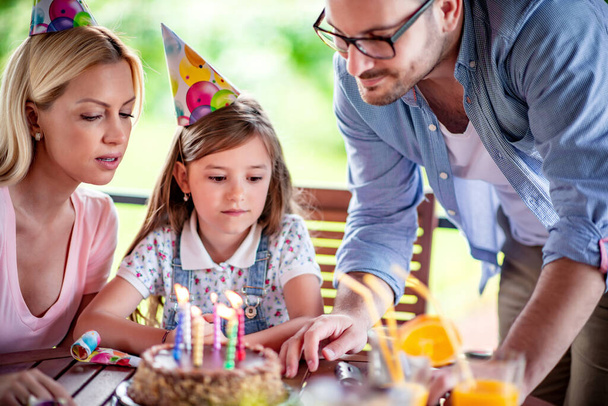 Father, mother and daughter are celebrating birthday at home. - Photo, Image