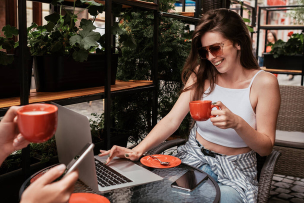 Két fiatal nő kávét iszik egy kávézóban a szabadban, Ebédidő koncepció, Brunette Girl in Focus - Fotó, kép