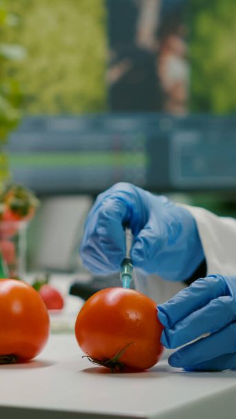 Close-up van chemicus wetenschapper die organische tomaat injecteert met pesticiden - Foto, afbeelding
