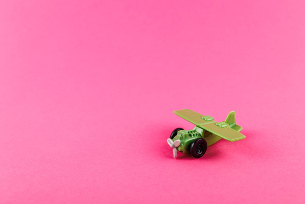 Small plastic airplane with copy space on pink background. Toy. - Photo, image