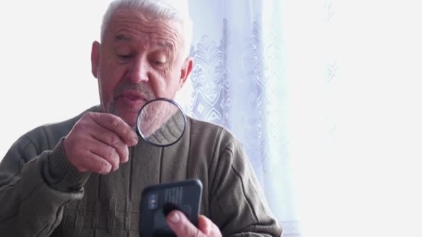 Ένας συνταξιούχος διαβάζει ένα μήνυμα σε ένα smartphone - Πλάνα, βίντεο