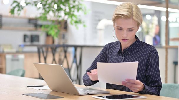 Молодая предпринимательница читает документы в офисе  - Фото, изображение