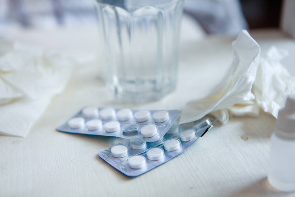 Een close-up van medicijnen. Voor het bed van de patiënt zijn gebruikt zakdoeken, pillen, neusdruppels. Het concept van de behandeling van verkoudheid. - Foto, afbeelding