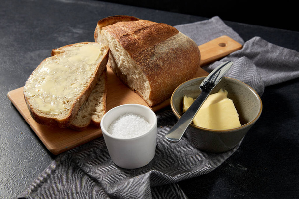 close up of bread, butter, knife and salt on towel - Foto, afbeelding