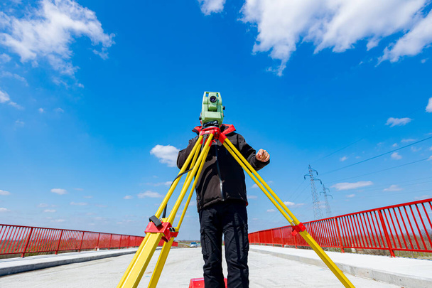 Ingeniero topógrafo está midiendo puente en construcción, sitio. Los topógrafos aseguran mediciones precisas antes de emprender grandes proyectos de construcción. - Foto, Imagen