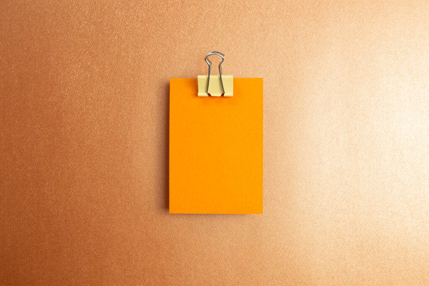 Bloc de notas en blanco con clip de metal sobre fondo naranja. vista superior, espacio de copia - Foto, Imagen