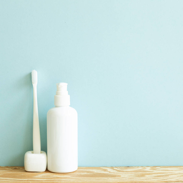 Cuidados com a pele e conceito spa. Garrafa de banheiro e escova de dentes na prateleira de madeira. céu azul fundo - Foto, Imagem
