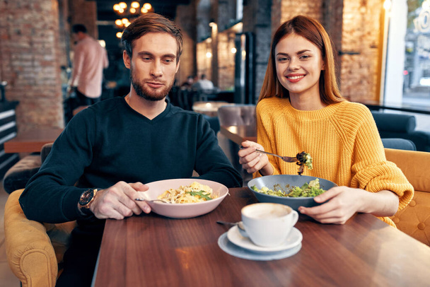 un hombre y una mujer están sentados en una mesa en un restaurante comida deliciosa comida que sirve platos - Foto, Imagen
