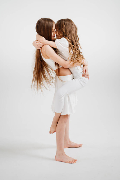 two cheerful girls with long hair in white clothes play, have fun.  - Fotó, kép