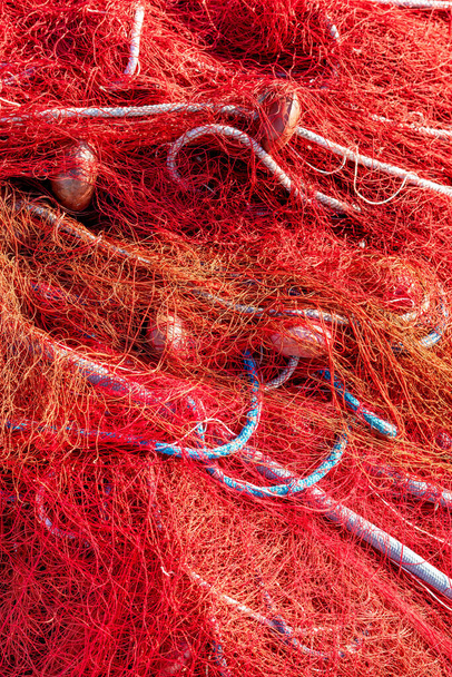 Rote Fischernetze mit Schwimmern und Seilen. Nahaufnahme, perfektes Bild für Fischerei, Aquakultur, Intensivfischerei und Umweltschutz. - Foto, Bild