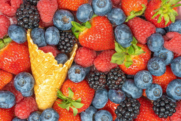 Hintergrund aus frischen Beeren, Blaubeeren, Himbeeren, Erdbeeren, Igel mit Waffelkegel. Es gibt einen Platz für den Text Konzept eines nützlichen Geschenks, Glückwunsch zum Urlaub - Foto, Bild