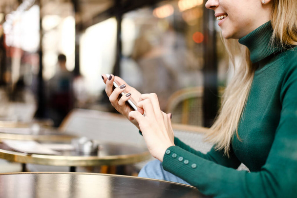 Rubia chica charlando por smartphne y sentado en la calle café. - Foto, imagen