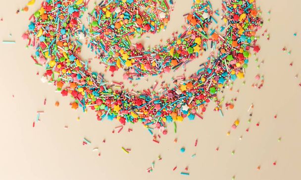 Spiraal van veelkleurige suikerhagelslag van verschillende vormen op een lichte achtergrond - Foto, afbeelding