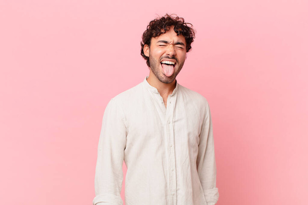 hispanic handsome man with cheerful, carefree, rebellious attitude, joking and sticking tongue out, having fun - Φωτογραφία, εικόνα
