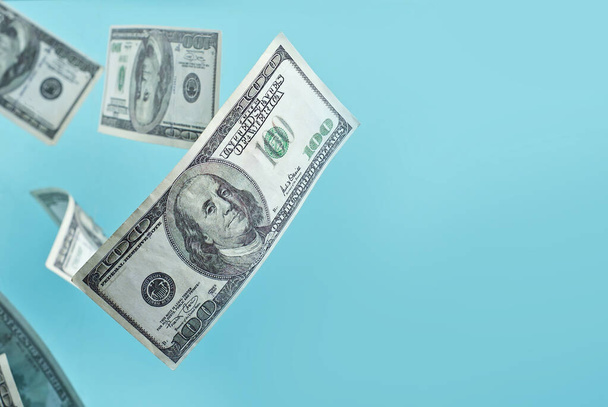 Green dollar bills on a blue background. 100 dollar bills close up. The concept of wealth and success. Money flies in the air. Copy space and free space for text near money. - Photo, image