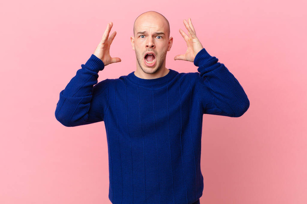 bald man screaming with hands up in the air, feeling furious, frustrated, stressed and upset - Foto, afbeelding