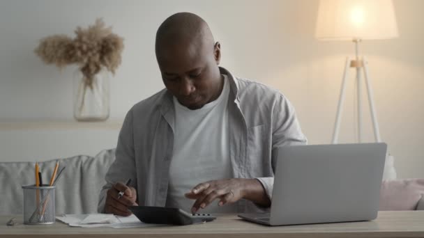 African American Man Calculating Expenses And Taking Notes Sitting Indoors - Metraje, vídeo
