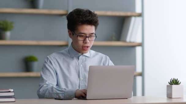 Jovem asiático nerd vestindo óculos lendo mensagem com ótimas notícias e desfrutando de realização, trabalhando em casa escritório - Filmagem, Vídeo