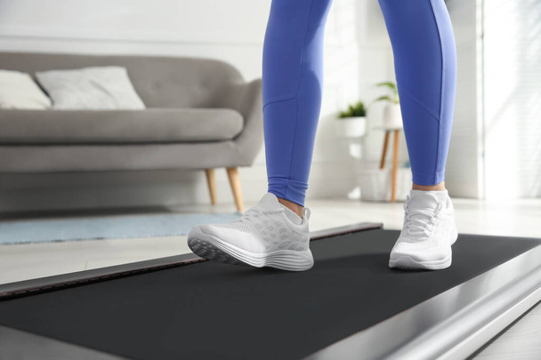 Sporty woman training on walking treadmill at home, closeup - Foto, afbeelding