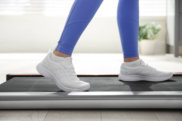 Sporty woman training on walking treadmill indoors, closeup - Fotografie, Obrázek