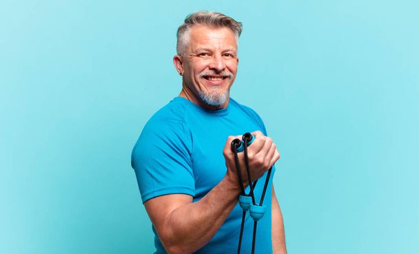 senior handsome man practising fitness and wearing sport clothes - Foto, afbeelding