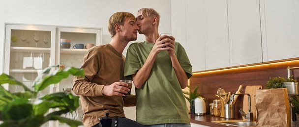 Tender homosexual couple of men hugging in kitchen - Fotó, kép
