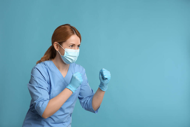 Médico com máscara protetora na luta posar no fundo azul claro, espaço para texto. Forte conceito de imunidade - Foto, Imagem