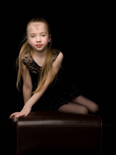 Cute little girl in a dance suit. On a black background. - Фото, изображение