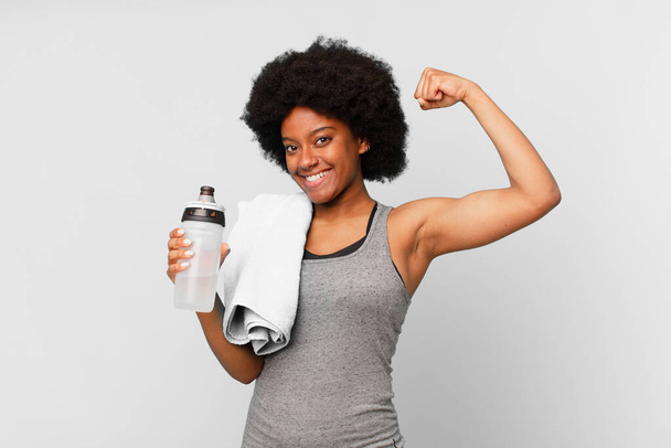 black afro fitness woman with a towel and water can - Valokuva, kuva