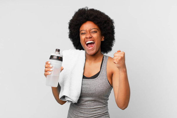black afro fitness woman with a towel and water can - Foto, imagen
