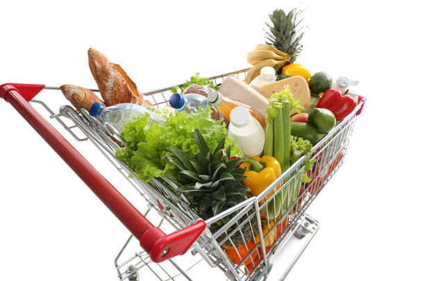 Shopping cart with groceries on white background - Фото, изображение
