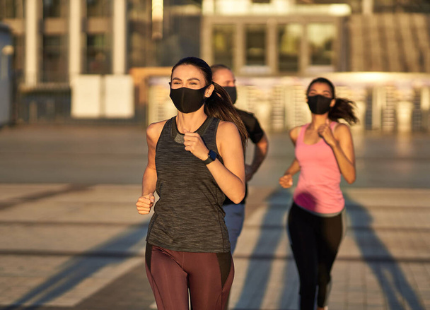 Urheilullinen nainen juoksee kadulla yhdessä muiden urheilijoiden kanssa - Valokuva, kuva