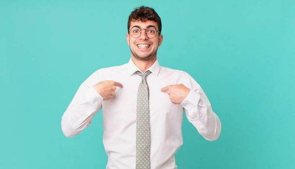 young businessman feeling happy, surprised and proud, pointing to self with an excited, amazed look - Foto, Imagen