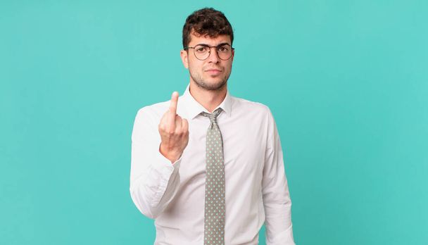 young businessman feeling angry, annoyed, rebellious and aggressive, flipping the middle finger, fighting back - Fotoğraf, Görsel