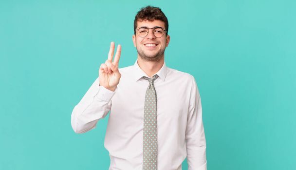 若い実業家は笑顔で友好的に見え2番目か2番目を前に手を挙げて数えます - 写真・画像