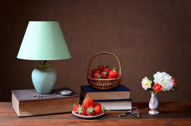 Candeeiro de mesa, livros, morangos e flores
 - Foto, Imagem