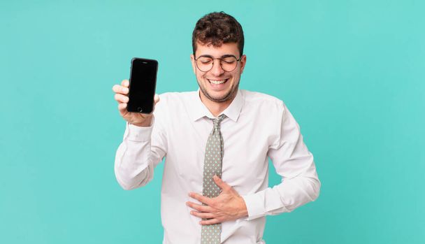 business with a smartphone laughing out loud at some hilarious joke, feeling happy and cheerful, having fun - Foto, imagen