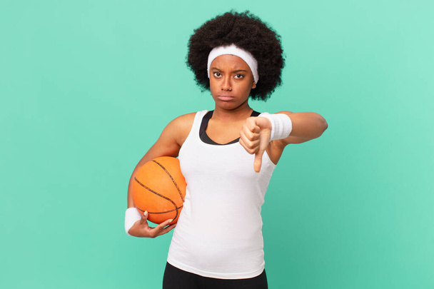 afro woman feeling cross, angry, annoyed, disappointed or displeased, showing thumbs down with a serious look. basketball concept - Foto, Imagem