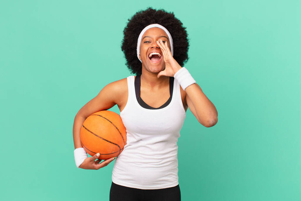 Afro kadın mutlu, heyecanlı ve pozitif hissediyor. Elleri ağızının yanında bağırarak bağırıyor. Basketbol konsepti - Fotoğraf, Görsel