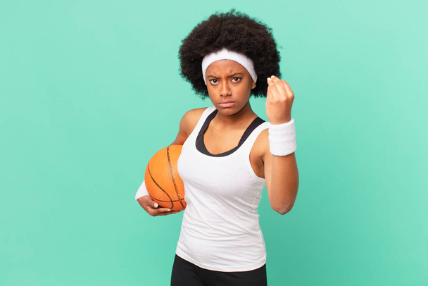 afro woman making capice or money gesture, telling you to pay your debts!. basketball concept - Photo, image