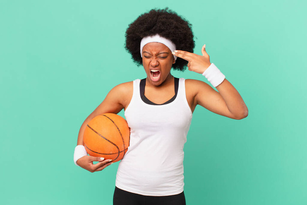 Afro kadın mutsuz ve stresli görünüyor, intihar jesti silahla işaret ediyor, kafasını işaret ediyor. Basketbol konsepti - Fotoğraf, Görsel