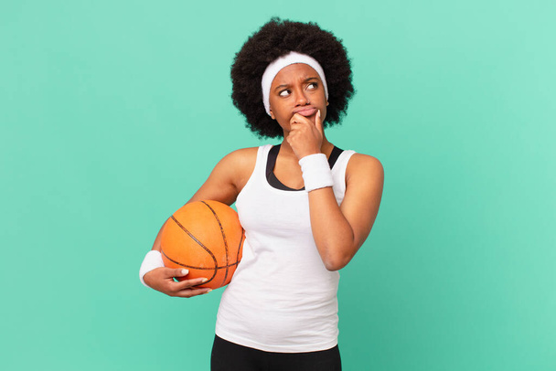 afro woman thinking, feeling doubtful and confused, with different options, wondering which decision to make. basketball concept - Foto, Bild