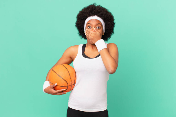 Afro kadın şok olmuş, şaşırmış bir ifadeyle ağzını kapatıyor ya sır saklıyor ya da "Eyvah" diyor. Basketbol konsepti - Fotoğraf, Görsel